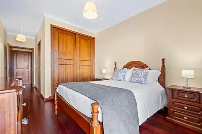 a bedroom with a large bed and a wooden cabinet at Casa Carlota by Atlântica in Santa Cruz