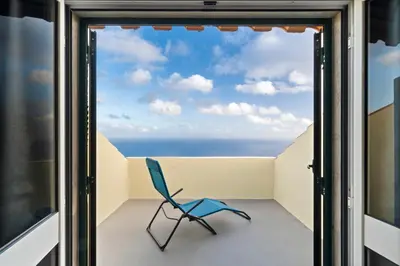a chair sits on a balcony with a view of the ocean at Casa Carlota by Atlântica in Santa Cruz