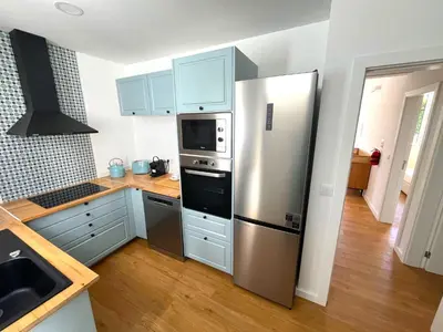 a kitchen with a stainless steel refrigerator and wooden floors at Casa da Porta Azul in Funchal