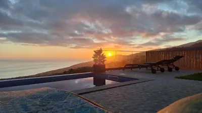 a pool with a bench and the sunset in the background at Vila Rouxinol in Arco da Calheta