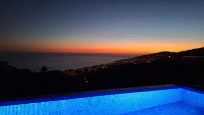 a swimming pool with a sunset in the background at Vila Rouxinol in Arco da Calheta