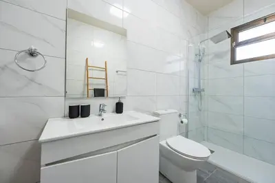 a white bathroom with a toilet and a sink at Casa Do Sol in Arco da Calheta