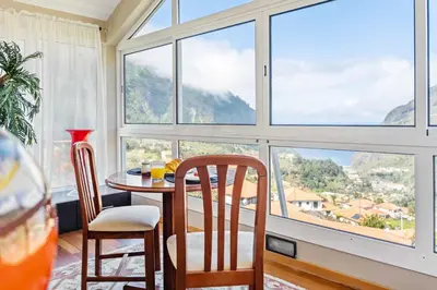 a dining room with a table and chairs and large windows at Landure by Homie in São Vicente