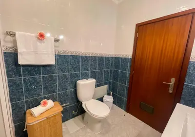 a bathroom with a toilet and a blue tiled wall at Villa Nunes in Funchal