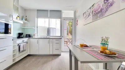 a kitchen with white cabinets and a table at Pino's Getaway by LovelyStay in Funchal