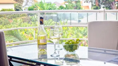 a bottle of wine and a bowl of grapes on a table at Pino's Getaway by LovelyStay in Funchal