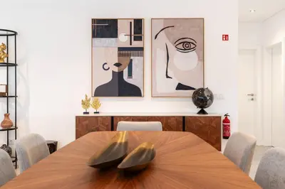 a dining room with a wooden table and some paintings at Oak Tree Ocean View in Ponta do Sol