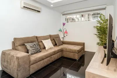 a living room with a brown couch and a tv at Tranquilidade, Quiet Apartament in Funchal City Center in Funchal