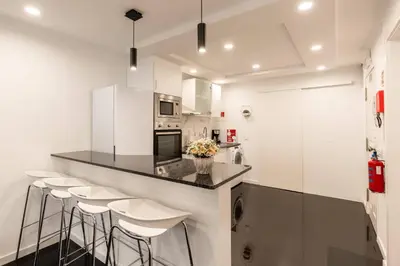 a kitchen with white cabinets and bar stools at Tranquilidade, Quiet Apartament in Funchal City Center in Funchal