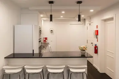 a kitchen with white cabinets and a counter with stools at Tranquilidade, Quiet Apartament in Funchal City Center in Funchal