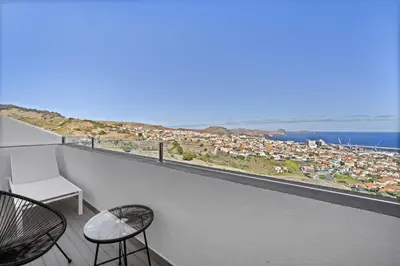 a balcony with a view of a city and the ocean at São Lourenço Guest House in Caniçal
