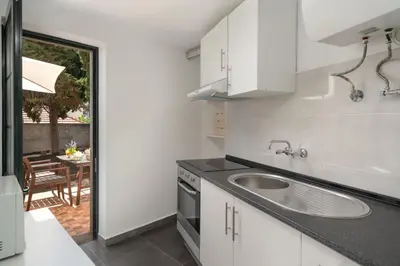 a white kitchen with a sink and a table at OurMadeira - Vintage Garden Apartment in Funchal