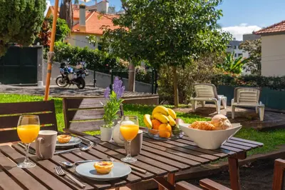 a wooden table with a bowl of fruit and glasses of orange juice at OurMadeira - Vintage Garden Apartment in Funchal