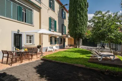 a courtyard with a table and chairs and an umbrella at OurMadeira - Vintage Garden Apartment in Funchal