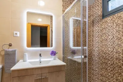 a bathroom with a sink and a shower with a mirror at Goncalves House - AC and private parking in Calheta