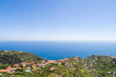 an aerial view of a village on a hill with the ocean at Goncalves House - AC and private parking in Calheta