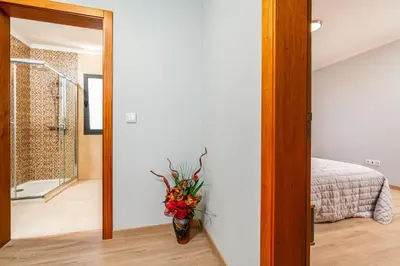a vase of flowers in a room with a mirror at Goncalves House - AC and private parking in Calheta