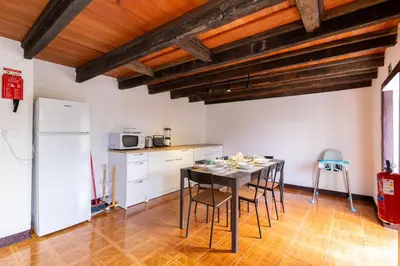 a kitchen with a table and chairs and a refrigerator at Sleep Among the Bananas! Rustic Cottage with Trails at Your Doorstep in Ponta do Sol