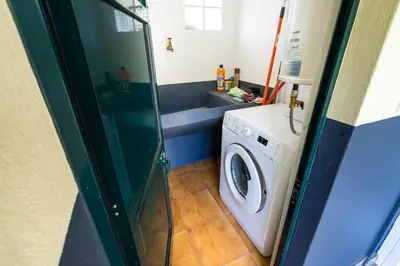 a bathroom with a washing machine and a sink at Sleep Among the Bananas! Rustic Cottage with Trails at Your Doorstep in Ponta do Sol