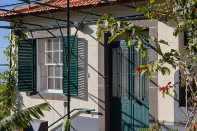 a house with a green door and window at Sleep Among the Bananas! Rustic Cottage with Trails at Your Doorstep in Ponta do Sol