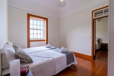 a white bedroom with a bed and a window at Sleep Among the Bananas! Rustic Cottage with Trails at Your Doorstep in Ponta do Sol