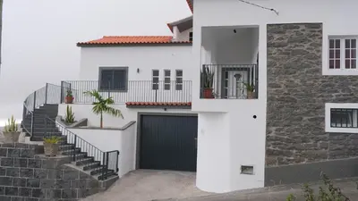 a white house with a black garage at Quinta do Carmo house with View in Calheta