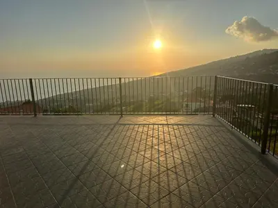 a balcony with a fence with the sunset in the background at Quinta do Carmo house with View in Calheta