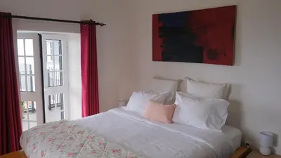 a white bed with a pink pillow on top of it at Quinta do Carmo house with View in Calheta
