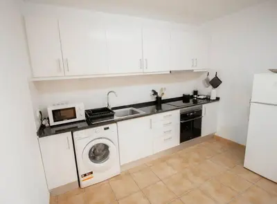 a kitchen with a washing machine and a microwave at Slowing Villas - Villa Âncora in Porto Santo