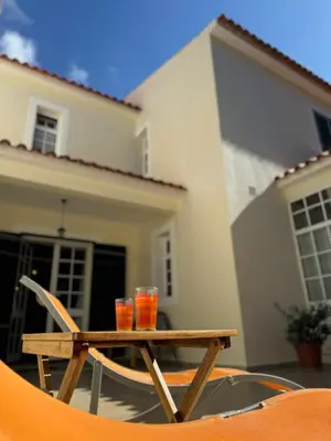 a wooden table with two drinks on it in front of a house at Moradia Abreu in Santa Cruz