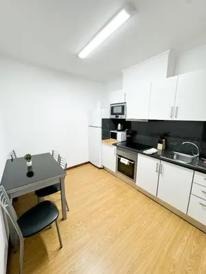 a kitchen with white cabinets and a table and a desk at Hostel Monaco in Funchal
