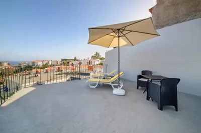 a patio with a table and a chair and an umbrella at Casa das Virtudes by Mth in Funchal