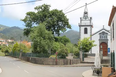 a church with a tower and a steeple in a town at OurMadeira - Prazeres Paradise in Prazeres