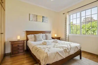 a bedroom with a bed with two night stands and a window at Palm Tree House by Homie in Ponta Delgada