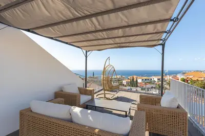 a balcony with wicker furniture and a view of the ocean at Flowers island house 5 in Funchal