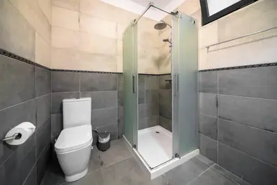 a bathroom with a toilet and a shower with a glass door at Casa Cabral by MTH in Ponta do Sol