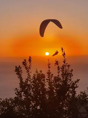 a person flying a paraglider over the sunset at Beautiful View 3 Arco da Calheta - Ilha da Madeira in Arco da Calheta