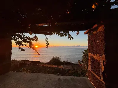 a view of the ocean from a house with the sunset at Suite Bela Vigia 3 in Jardim do Mar