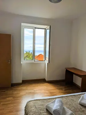 a white room with a window and a bed and a desk at Sea House in Funchal
