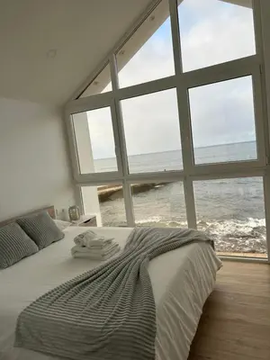 a bedroom with a large bed with a view of the ocean at Casa dos Anjos in Vila do Porto