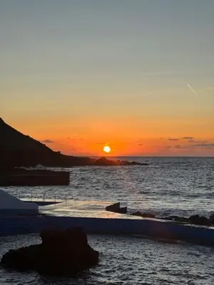 a sunset over the ocean with the sun setting at Casa dos Anjos in Vila do Porto