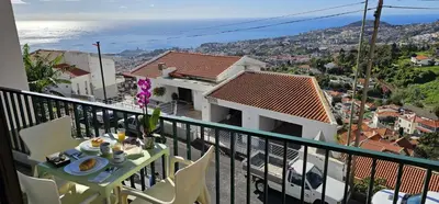 a balcony with a table and chairs and the ocean at Margarita House in Funchal
