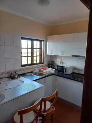 a kitchen with white cabinets and a table and chairs at Casa Afonso a getaway apartment in Arco da Calheta