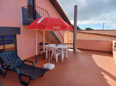 a cocacola umbrella and a table and chairs on a balcony at Casa Afonso a getaway apartment in Arco da Calheta