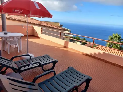 a patio with two chairs and a table and an umbrella at Casa Afonso a getaway apartment in Arco da Calheta