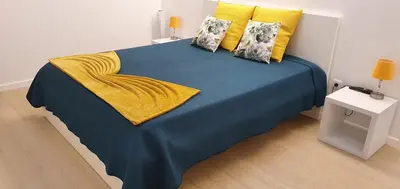 a large bed with a blue blanket and yellow pillows at Sea&Sunrise Village in Caniço