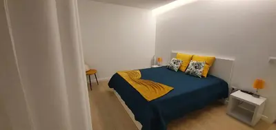 a bedroom with a bed with blue sheets and yellow pillows at Sea&Sunrise Village in Caniço