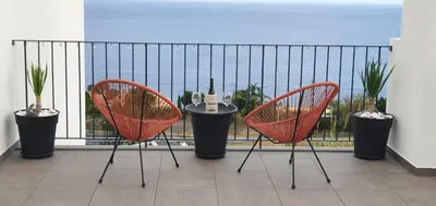 two chairs and a table on a balcony with the ocean at Sea&Sunrise Village in Caniço