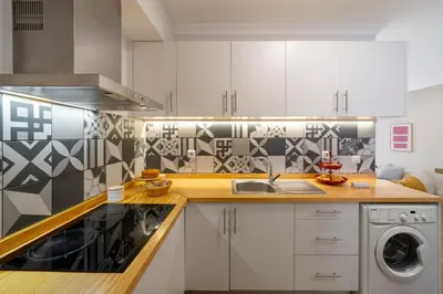 a kitchen with white cabinets and a washer and dryer at Loft Arrifes by An Island Apart in Funchal