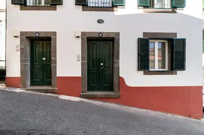 two green doors on the side of a building with windows at Loft Arrifes by An Island Apart in Funchal